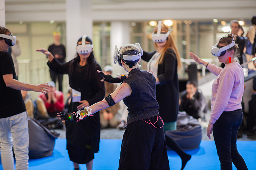 Foto von Tänzer:in und 4 Mitspielenden im Kreis mit VR-Brillen